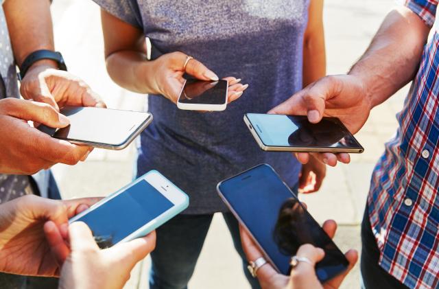 5 friends with smartphones, close up.