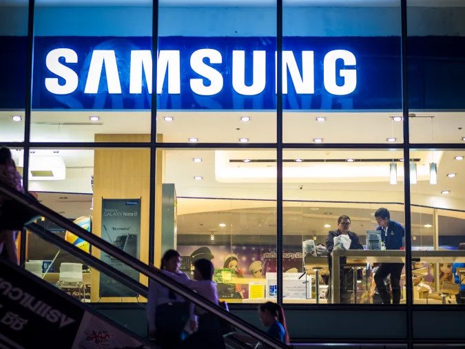 Bangkok, Thailand - November 1, 2012: Exterior view of a Samsung shop in the Siam Square area of Bangkok at night. people can be seen inside the store and making their way up an escalator outside. Image captured from the public walkway.