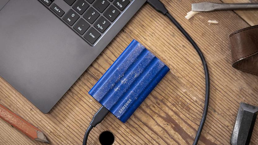 A photo of a Samsung T7 Shield Portable SSD plugged into a laptop on a table.