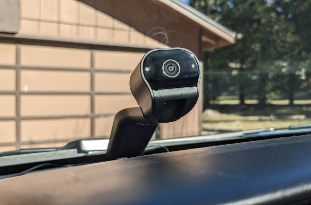 A Ring Car Cam installed on the dashboard of a car with a garage door in the background, seen from a drivers perspective.