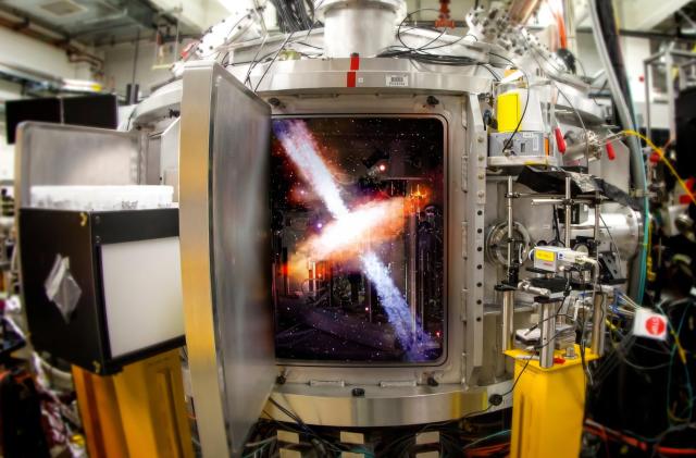 Photo of a complex device in a lab made mostly of metal with various wires and yellow areas. A door opens that appears to reveal some sort of X-shaped astronomical figure inside the machine's window.