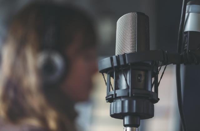 Close up of microphone in radio broadcast studio and female radio host on the background