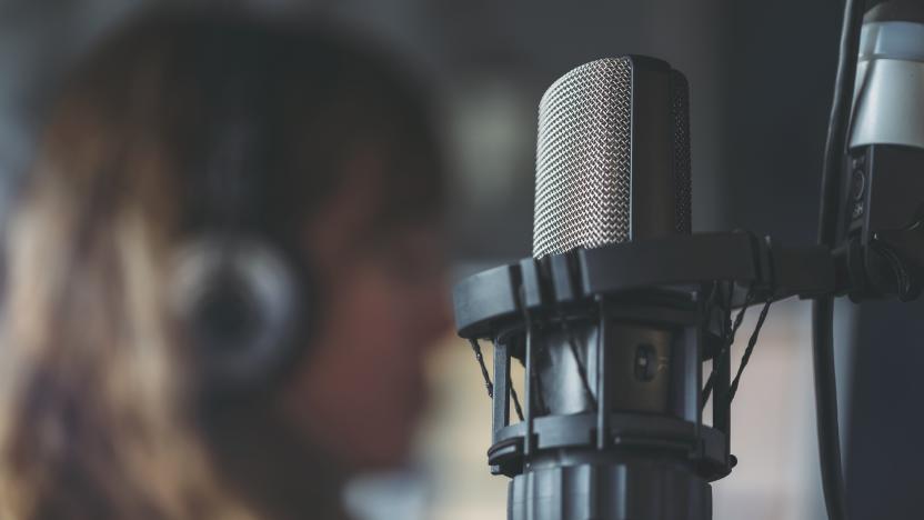 Close up of microphone in radio broadcast studio and female radio host on the background