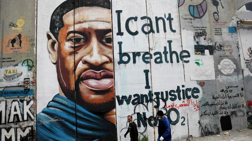 People walk past a mural showing the face of George Floyd, an unarmed handcuffed black man who died after a white policeman knelt on his neck during an arrest in the US, painted on a section of Israel's controversial separation barrier in the city of Bethlehem in the occupied West Bank on March 31, 2021. - The teenager who took the viral video of George Floyd's death said on March 30, at the trial of the white police officer charged with killing the 46-year-old Black man that she knew at the time "it wasn't right." Darnella Frazier, 18, was among the witnesses who gave emotional testimony on Tuesday at the high-profile trial of former Minneapolis police officer Derek Chauvin. Chauvin, 45, is charged with murder and manslaughter for his role in Floyd's May 25, 2020 death, which was captured on video by Frazier and seen by millions, sparking anti-racism protests around the globe. (Photo by Emmanuel DUNAND / AFP) (Photo by EMMANUEL DUNAND/AFP via Getty Images)