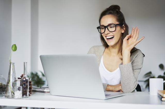 Young woman laughing during video chat at desk