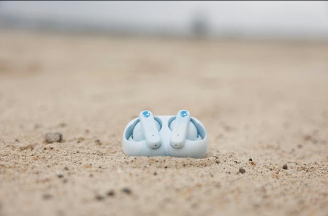 An image of earbuds in the sand. 