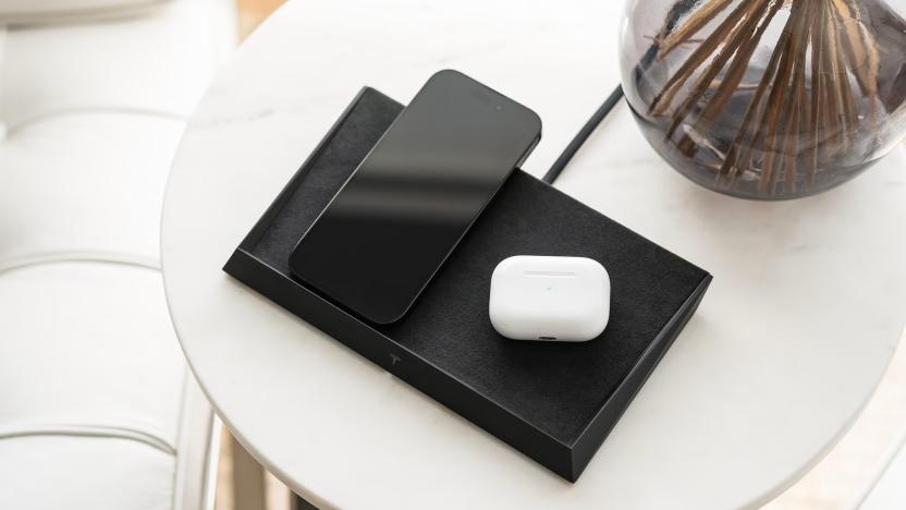 It's a pile of black square on a round white table next to a glass vase with a phone and earbud case sitting atop it. 