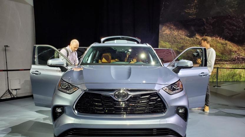 A front-view of a Toyota vehicle on display at the New York Auto Show, with doors open and people looking in.