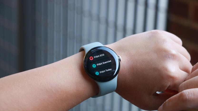 The Pixel Watch on a person's wrist, showing three apps. From top to bottom, they are "Fitbit ECG," "Fitbit Exercise" and "Fitbit Today."