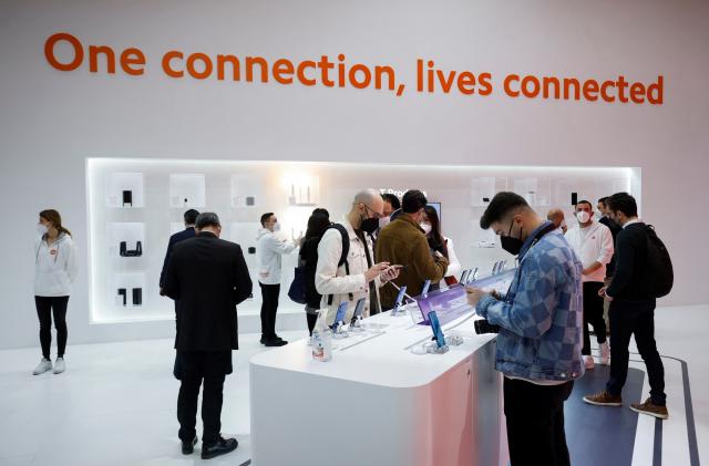 People stand while look at devices at Xiaomi during GSMA's 2022 Mobile World Congress (MWC), in Barcelona, Spain March 1, 2022. REUTERS/Albert Gea