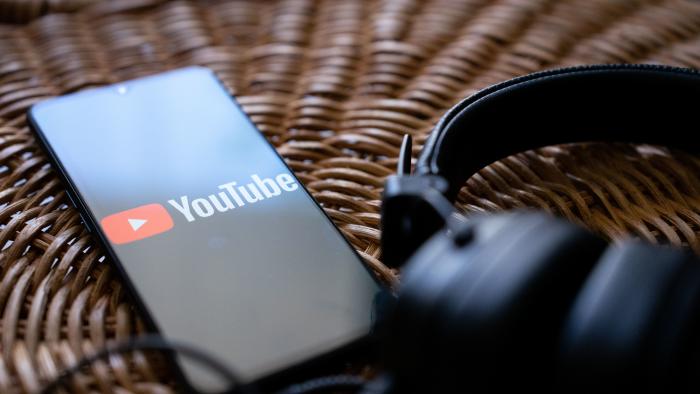 Headphones connected to a mobile phone with the logo of You tube on its screen. (Photo by Nikos Pekiaridis/NurPhoto via Getty Images)