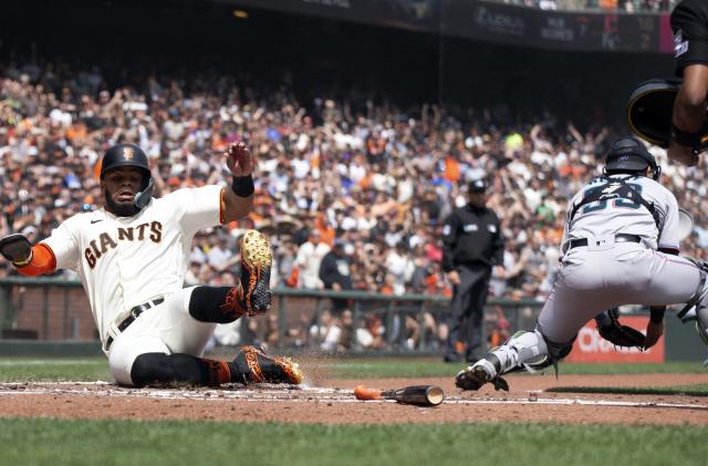 Apr 10, 2022; San Francisco, California, USA; San Francisco Giants left fielder Heliot Ramos, left, slides safely past Miami Marlins catcher Payton Henry (59) as he scores on a double by Mauricio Dubon during the second inning at Oracle Park. Mandatory Credit: D. Ross Cameron-USA TODAY Sports