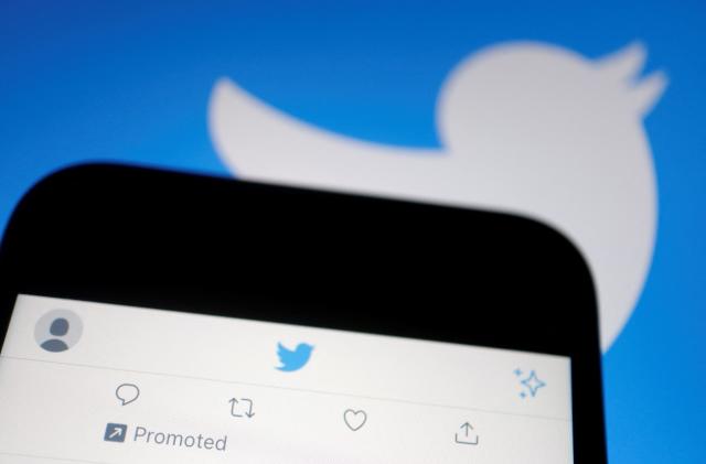 A promoted tweet on Twitter app is displayed on a mobile phone near a Twitter logo, in this illustration picture taken September 8, 2022. REUTERS/Florence Lo/Illustration