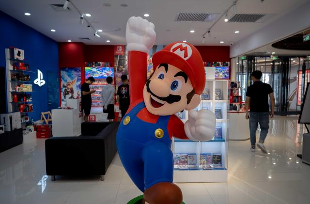 TIANJIN, CHINA - 2021/07/20: A cartoon figurine of Super Mario Bros. stands in front of a Nintendo Switch store in a shopping market.  By the end of June 2021, Nintendo's total global sales of Switch (including Switch and Switch Lite) have reached 87.43 million units, surpassing PS3 and becoming the seventh best selling host in Nintendo's history. (Photo by Zhang Peng/LightRocket via Getty Images)