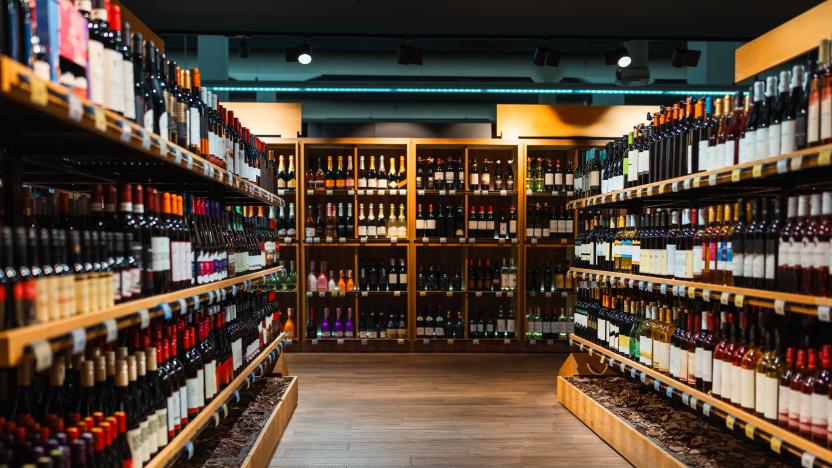 Liquor store background. Alcohol retail industry. Wine bottles on shelves in wine shop.