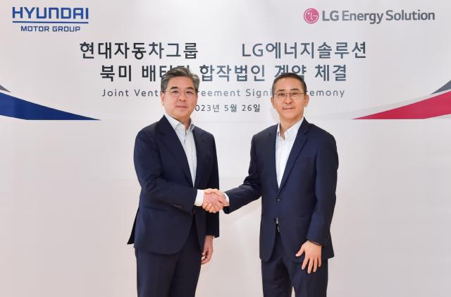Jaehoon Chang, President and CEO of Hyundai Motor Company, on the left and Youngsoo Kwon, CEO of LG Energy Solution, on the right. They're shaking hands in front of a while wall announcing their joint venture agreement signing ceremony.