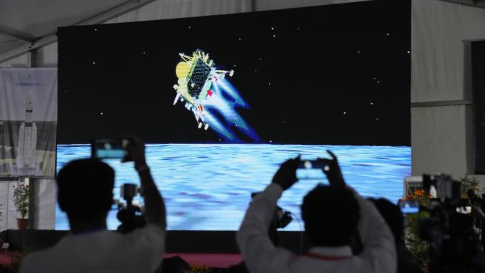Journalists film the live telecast of spacecraft Chandrayaan-3 landing on the moon at ISRO's Telemetry, Tracking and Command Network facility in Bengaluru, India, Wednesday, Aug. 23, 2023. India lands a spacecraft near the moon’s south pole, becoming the fourth country to touch down on the lunar surface. (AP Photo/Aijaz Rahi)