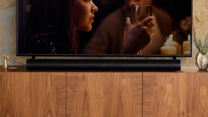 The Sonos Arc sits on a wooden cabinet with a TV above it. 