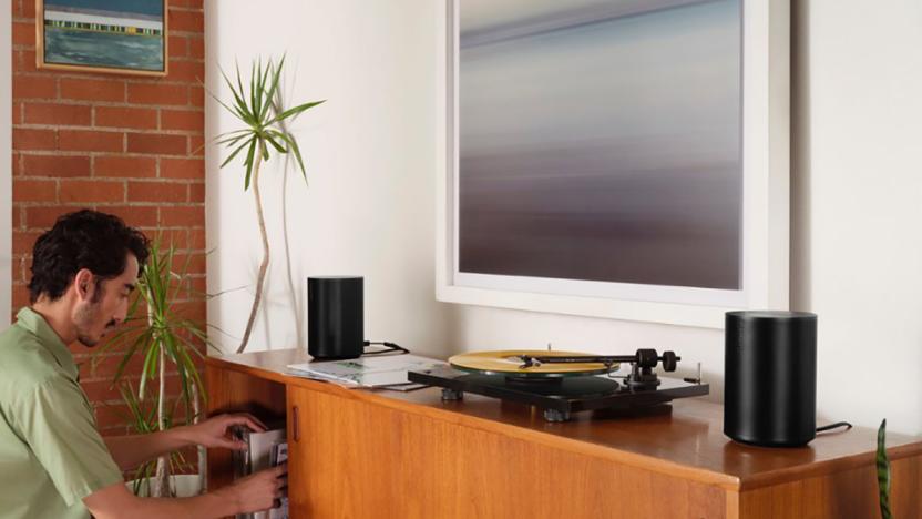 Two Sonos Era 100 speakers sit on a cabinet next to a turntable