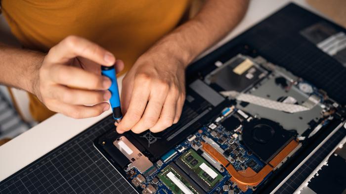 High angle view of unrecognizable Caucasian man with screwdriver repairing his laptop