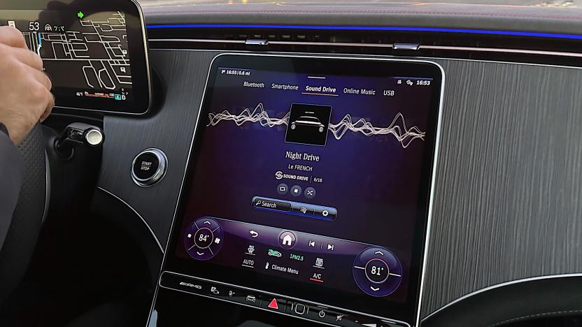 Image of the media unit at the front of a Mercedes AMG showing MBUX SOUND DRIVE, a new immersive audio system coming mid-2024. The image is of a car dashboard with a street scene in the upper third.