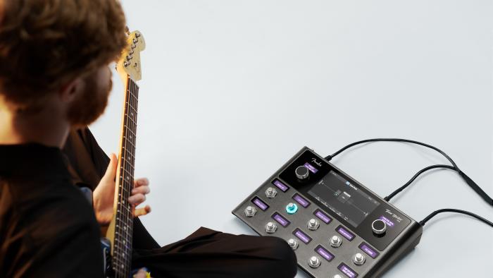 A bearded hipster plays guitar with the Tone Master Pro. 
