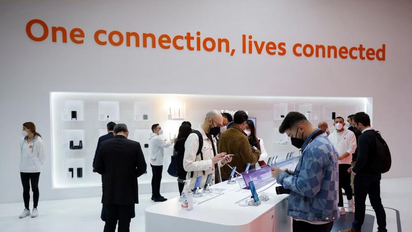 People stand while look at devices at Xiaomi during GSMA's 2022 Mobile World Congress (MWC), in Barcelona, Spain March 1, 2022. REUTERS/Albert Gea