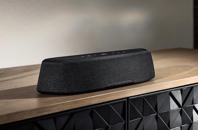 The Polk Audio MagniFi Mini AX soundbar sits alone on a wooden media center console, with no TV in sight.