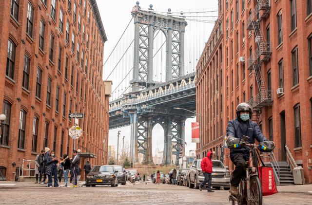 NEW YORK, NEW YORK - DECEMBER 22: A GrubHub delivery person rides a bicycle by Manhattan Bridge on December 22, 2020 in the Brooklyn borough of New York City. The pandemic continues to burden restaurants and bars as businesses struggle to thrive with evolving government restrictions and social distancing plans which impact keeping businesses open yet challenge profitability. (Photo by Noam Galai/Getty Images)