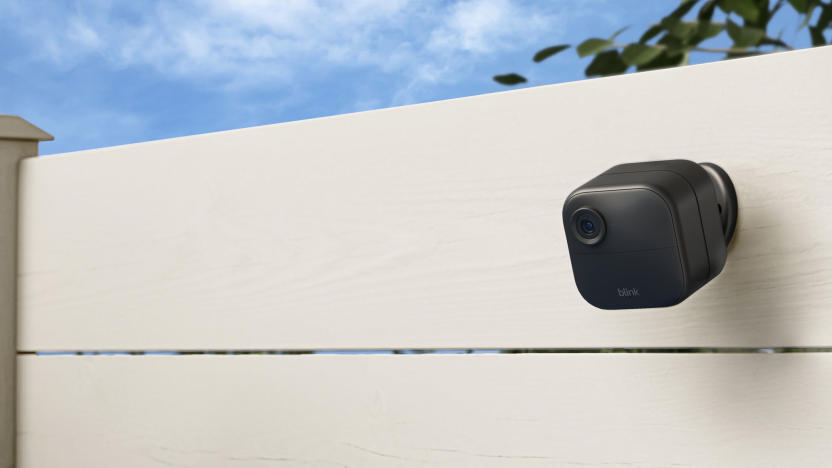 Image of the Blink Outdoor 4 with its external battery pack mounted behind it on a white fence.