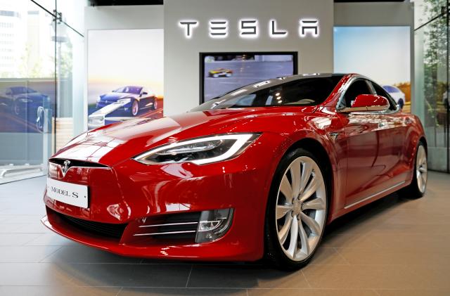 A red Tesla shown inside a Tesla showroom.