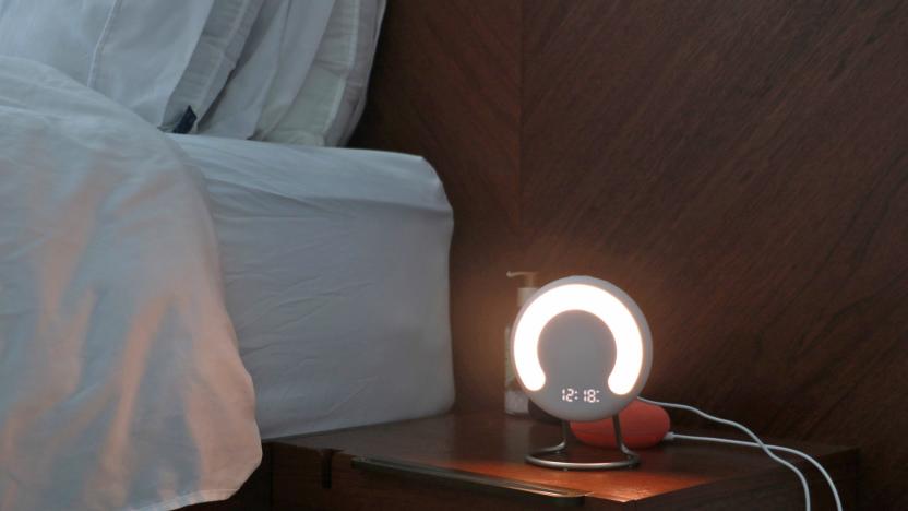 The Amazon Halo Rise on a nightstand in the dark with a the time and a semi-circle lit up on its front.