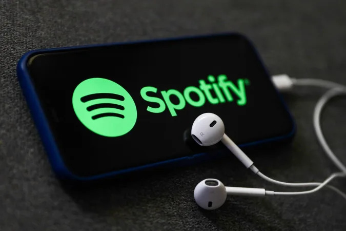 Spotify logo displayed on a phone screen and headphones are seen in this illustration photo taken in Poland on October 18, 2020.   (Photo Illustration by Jakub Porzycki/NurPhoto via Getty Images)