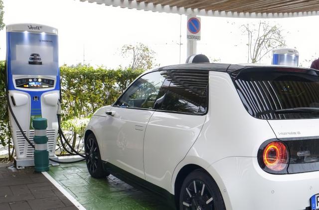 A small white Honda car sits at an EV station.