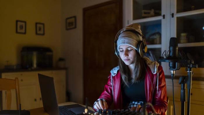 Teenage DJ streaming live music from home using laptop and mixer