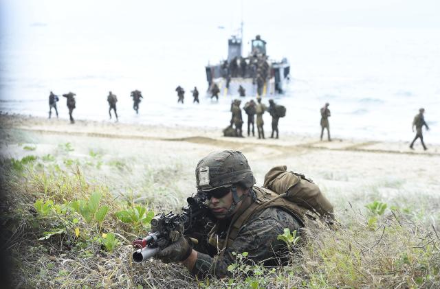 BOWEN, AUSTRALIA - JULY 22: A U.S Marine is seen as troops disembark from landing craft in the background on July 22, 2019 in Bowen, Australia. Exercise Talisman Sabre 2019 is the largest exercise that the Australian Defence Force (ADF) conducts with all four services of the United States armed forces. The biennial exercise focuses on crisis action planning and humanitarian missions, enhancing participating nations' capabilities to deal with regional contingencies and terrorism. It is the first time the NZDF has been invited to participate fully, with NZDF personnel to be working as part of a large force led by the Australians and NZDF military assets will be integrated with those of the ADF and the US armed forces. (Photo by Ian Hitchcock/Getty Images)