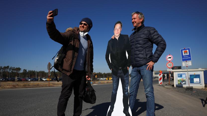 Tesla fan Martin Wrobel poses with a man and a paper figure of Elon Musk outside the new Tesla Gigafactory for electric cars in Gruenheide, Germany, March 22, 2022. REUTERS/Lisi Niesner