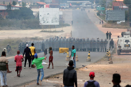 Image result for People throw stones at Venezuelan national guard members, at the border, seen from Pacaraima, Brazil