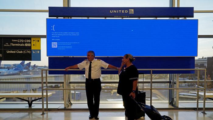 United Airlines employees wait by a departures monitor displaying a blue error screen, also known as the “Blue Screen of Death” inside Terminal C in Newark International Airport, after United Airlines and other airlines grounded flights due to a worldwide tech outage caused by an update to CrowdStrike's "Falcon Sensor" software which crashed Microsoft Windows systems, in Newark, New Jersey, U.S., July 19, 2024. REUTERS/Bing Guan     TPX IMAGES OF THE DAY