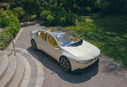 A white BMW is on a gravel path with steps on one side and grass on the other. 