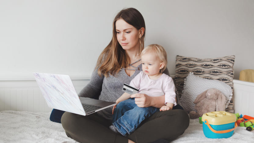 Young Caucasian mother with baby shopping online from home. Stay at home single mom with kid toddler daughter buying ordering products food on Internet and paying with credit card.