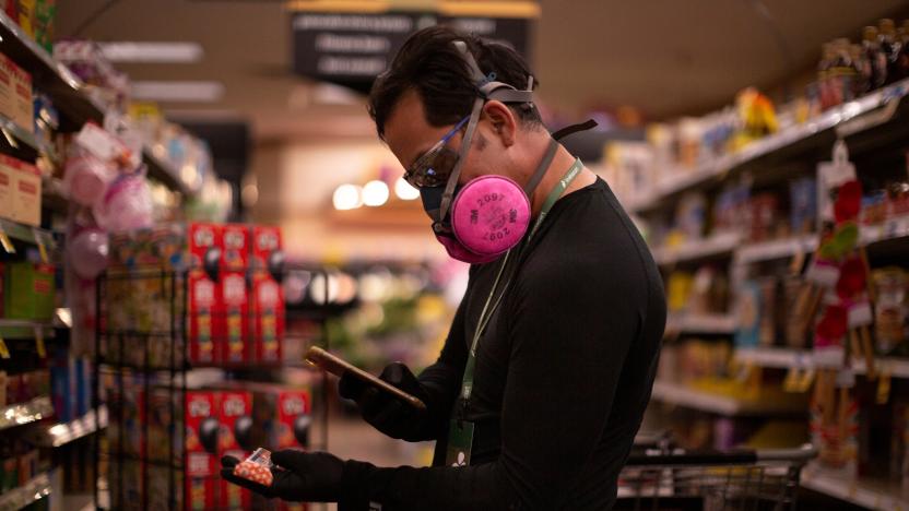 Instacart employee Eric Cohn, 34, uses his phone to scan an item for a delivery order he is preparing from Fry's grocery store while wearing a respirator mask to help protect himself and slow the spread of the coronavirus disease (COVID-19) in Tucson, Arizona, U.S., April 4, 2020. Picture taken April 4, 2020.  REUTERS/Cheney Orr