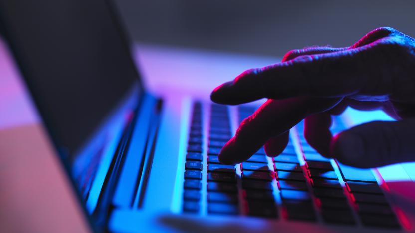 Silhouette of male hand typing on laptop keyboard at night