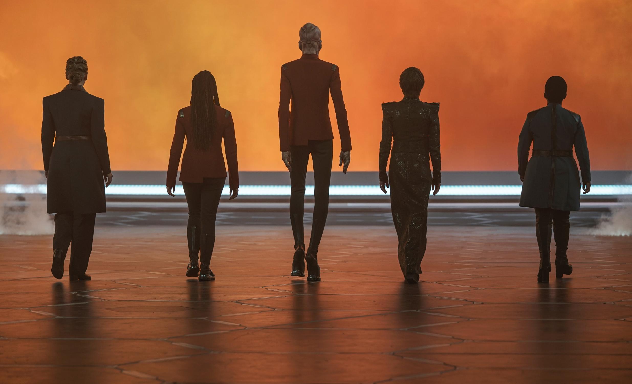 Five Star Trek: Discovery characters walk away into an orange void with their backs to the camera.