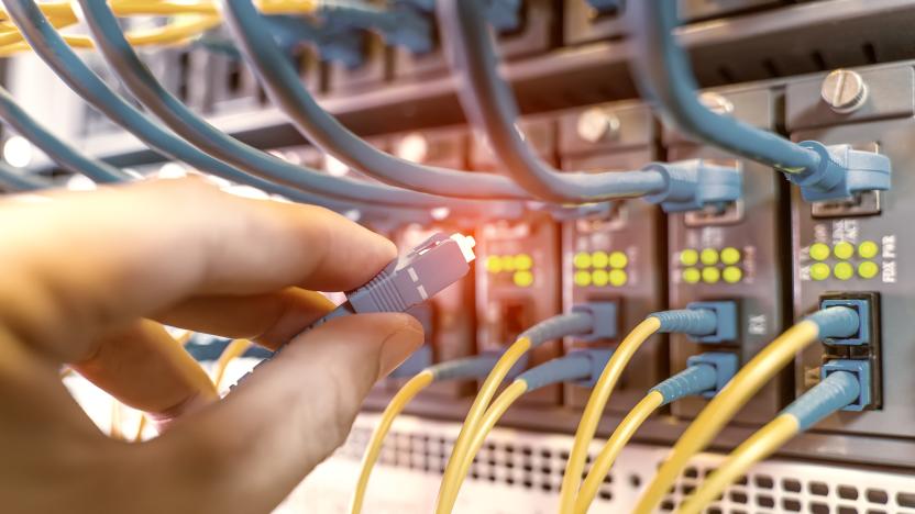 hand with fiber network cables connected to servers in a datacenter