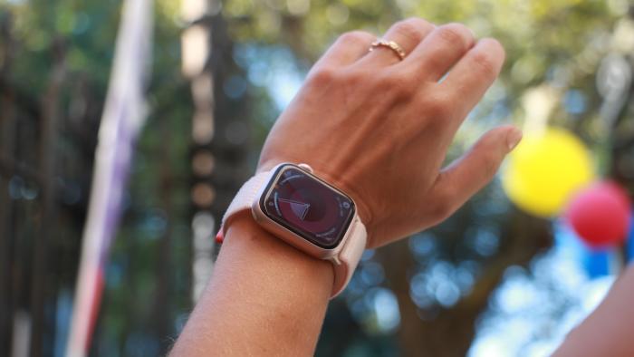 The Apple Watch Series 9 on a wrist in mid-air, with some balloons in the blurred background.