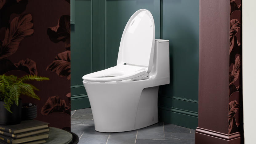 A white toilet (with a smart bidet seat) sitting in an upscale bathroom (green walls with floral patterns outside the throne room).