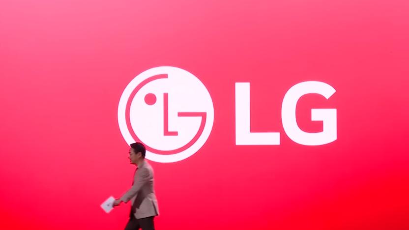 Screenshot of an LG executive walking to camera-left in front of an enormous screen showing an LG logo against a red background.