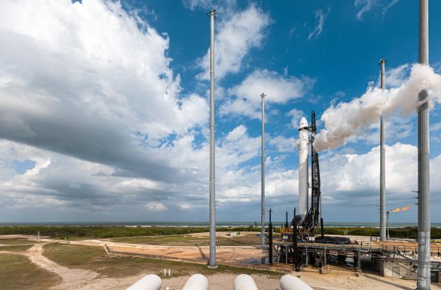 Relativity Space's Terran 1 rocket against a background of blue sky, clouds and palm trees.