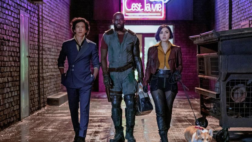 A still promoting the new live-action Netflix series 'Cowboy Bebop' showing three people and a corgi walking down a water-slicked back alley.